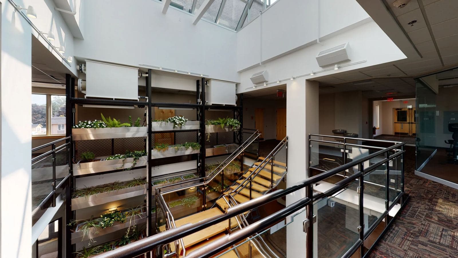 Skylit atrium at I-Square with a multi-level living plant wall and open staircase